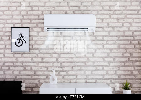 White Air Conditioner Blowing Cold Air On Brick Wall In Living Room Stock Photo