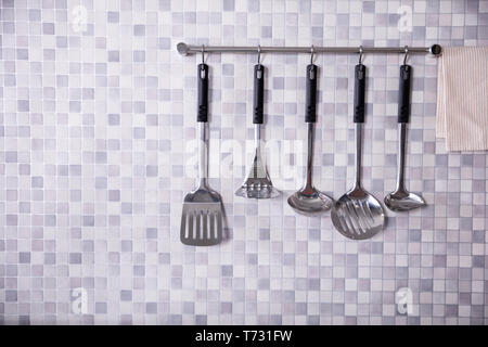 Set Of Metal Kitchen Utensils Hanging On Wall Stock Photo