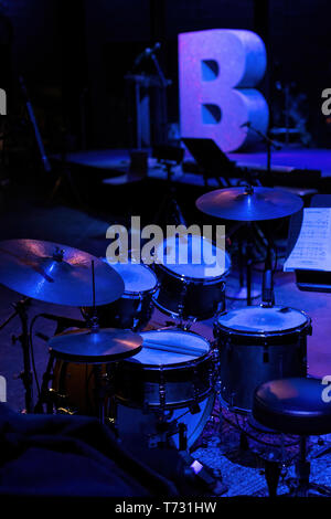 A set of drums on a stage doused in pale blue light Stock Photo