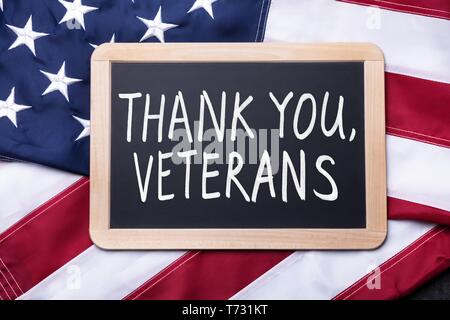 Top View Of Thank You Veterans Text Written On Slate Over American Flag Stock Photo