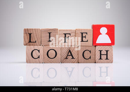 Red Human Figure Block Next To Word Life Coach On Wooden Block Stock Photo