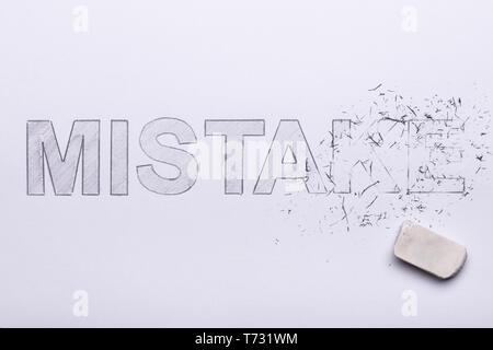 Close-up Of Pencil Eraser Erasing Mistake Word On White Paper Stock Photo