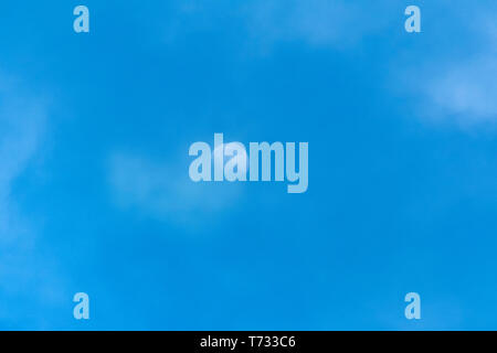 Moon during the day, partially hidden by mist and clouds Stock Photo