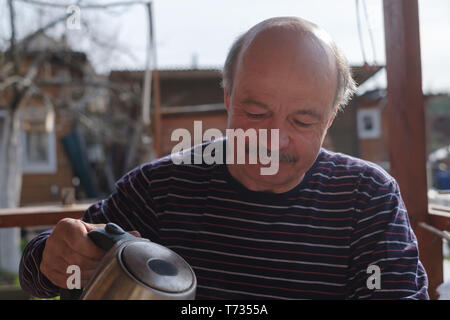 Thoughtful mature male drinking tea holding teapot Stock Photo