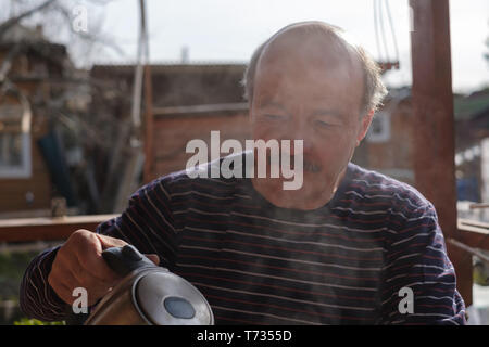 Thoughtful mature male drinking tea holding teapot Stock Photo