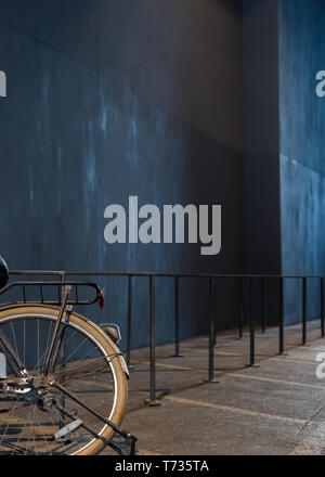 The rear wheel of an old bicycle in front of a blue wall Stock Photo