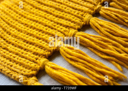 Knitted wool yellow scarf texture on wooden background Stock Photo