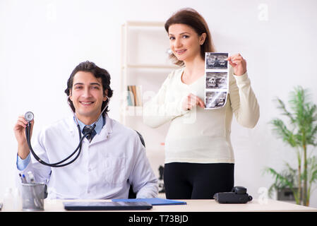 Old pregnant woman visiting young male doctor Stock Photo