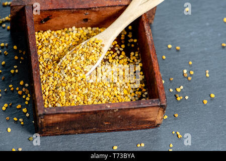 close-up of bees pollen granules inside a small wooden box, slate background Stock Photo