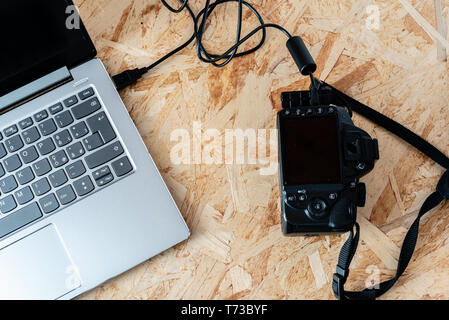 notebook connected to a digital SLR camera with usb cable, thetering mode, on a desktop Stock Photo