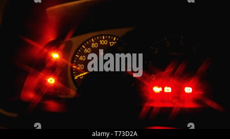 look at the cockpit and the speedometer inside a car, on the side the red function lights glow in the dark at night, in the colours black and very red Stock Photo