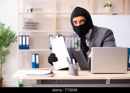 Male gangster stealing information from the office Stock Photo