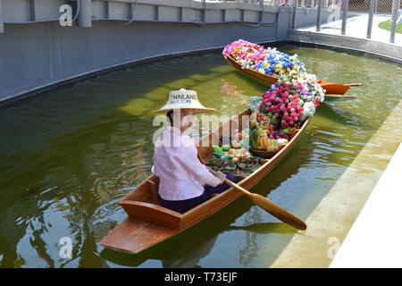 Milan/Italy - June 30, 2015: Woman sitting in traditional Thai wooden floating market boat filled with flowers anchored at Thailand Milano EXPO 2015. Stock Photo