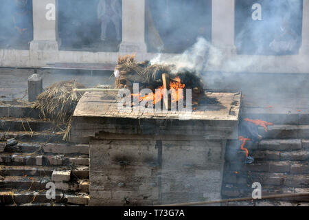 Hindu cremation process in progress near a temple Pashupatinath, Kathmandu, Nepal Stock Photo