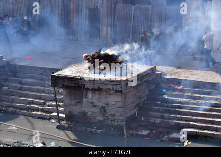 Hindu cremation process in progress near a temple Pashupatinath, Kathmandu, Nepal Stock Photo