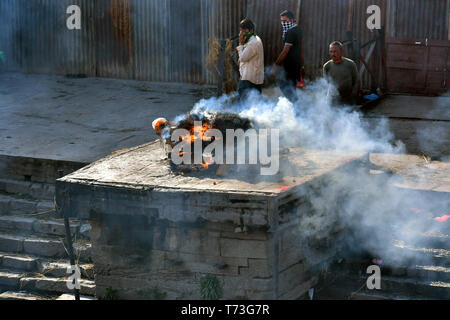 Hindu cremation process in progress near a temple Pashupatinath, Kathmandu, Nepal Stock Photo