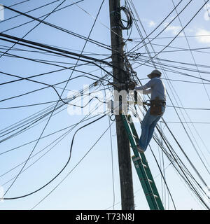 Electrician repairing power line cables on a post,French Harbour; Roatan, Bay Islands Department, Honduras Stock Photo