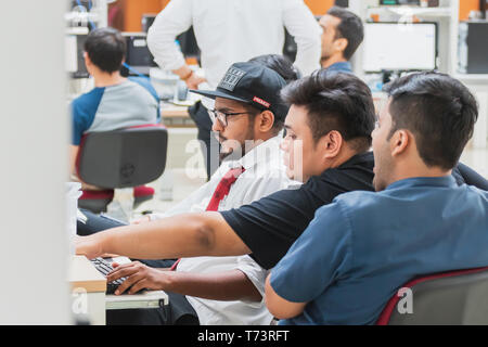 Group of Asian university computer engineering students working and discuss how to solve computer programming problems in an assignment Stock Photo