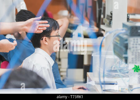 Portrait of asian university student working on computer network project in a group with server and other LAN cable in the foreground Stock Photo