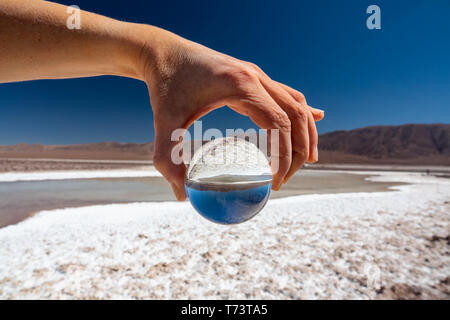 Hand holding glass ball at salt lakes in Atacama Stock Photo