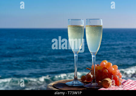 Champagne, prosecco or cava served with pink grape in two glasses on outside terrace with sea view close up Stock Photo