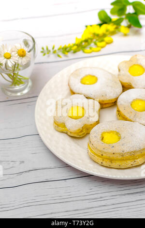 Easter biscuits like eggs with citrus cream on white wooden table Stock Photo
