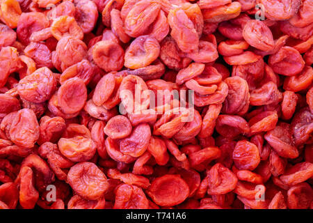 Dried apricot fruit on sun pattern background. Organic natural dried apricots from farm. Dark orange dried apricot fruit closeup macro. Dry fruits bac Stock Photo