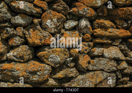 Close-up of wall made of rough stones covered by moss and lichens at Evoramonte. A tiny fortified civil parish with an old castle in Portugal. Stock Photo