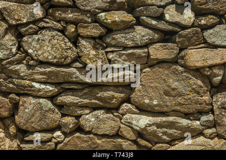 Close-up of wall made of rough stones covered by moss and lichens at Evoramonte. A tiny fortified civil parish with an old castle in Portugal. Stock Photo