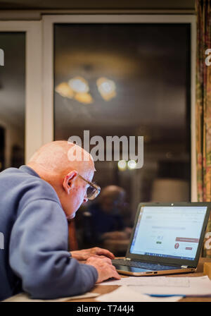 Old man of 93 years having trouble using his computer to check his finances online,very challenging for old people. Stock Photo