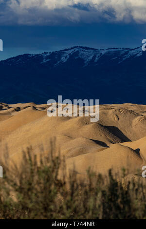 Sun and shade on sand/gravel quarry hills, with foothills and mountains in background Stock Photo