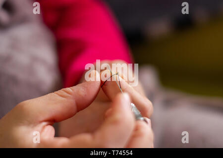 Woman cutting and knotting a thread on a needle before sewing Stock Photo