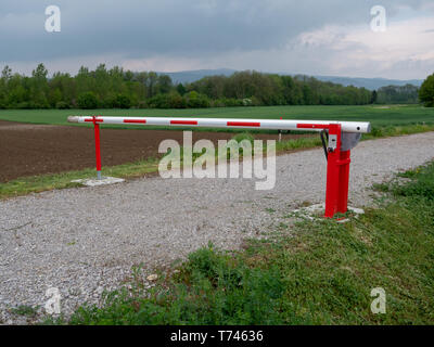 Closed Red and White Boom Gate or Boom Barrier on a Gravel Path in the Countryside Stock Photo