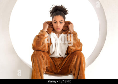 Young woman in bunny kigurumi sitting in hole isolated on white background looking camera serious Stock Photo