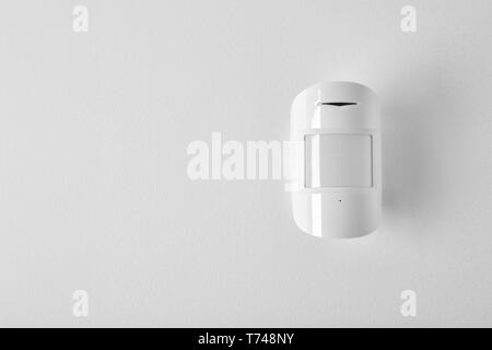 Modern motion sensor on wall indoors Stock Photo