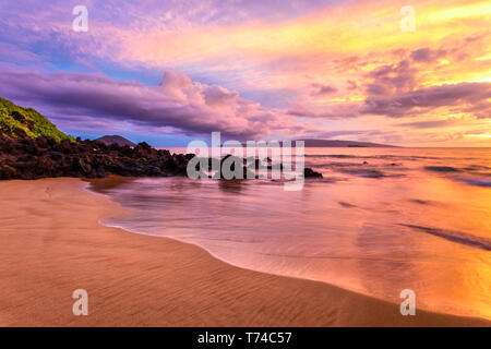 Dramatic clouds during a sunset on a deserted beach; Makena, Maui, Hawaii, United States of America Stock Photo