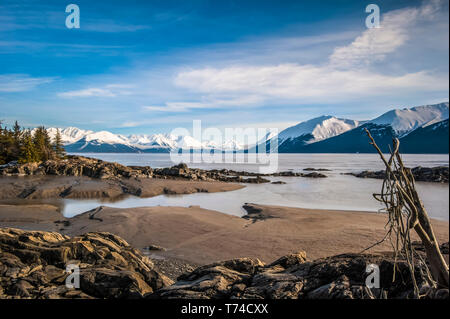 The in-coming tide on a calm winter day on the Turnagain Arm in South-central Alaska. The Chugach State Park and Chugach Mountains are in the backg... Stock Photo