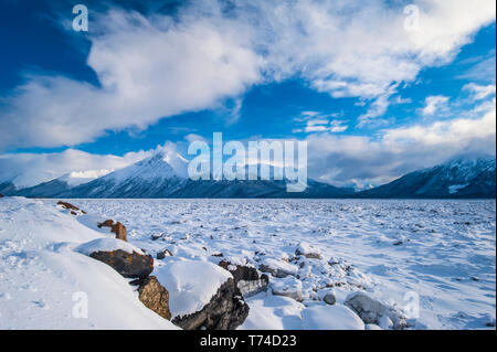 A landscape of clouds over the frozen Cook Inlet in South-central Alaska with the Chugach Mountains in the background on a winter day Stock Photo