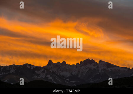 Intense red sunset over a distant range of sharp snowy mountain peaks; Mendoza, Argentina Stock Photo