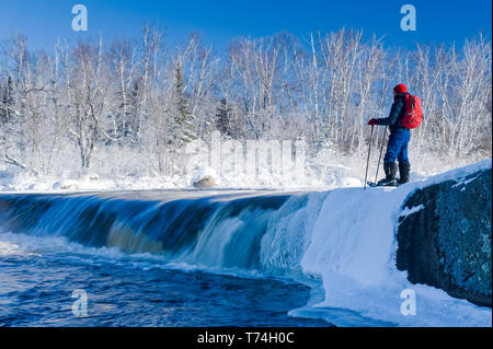 Snowshoeing in winter along Whiteshell River at Rainbow Falls, Whiteshell Provincial Park; Manitoba, Canada Stock Photo