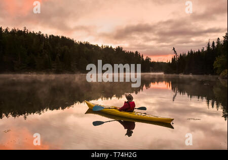 A man kayaking at sunset in the Rushing River, near Kenora; Ontario, Canada Stock Photo