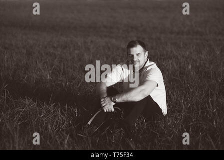 A casual portrait of a farmer sitting in field on a nice summers day. Stock Photo