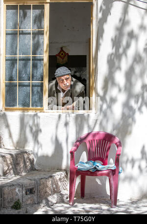 kashan, Iran, 25th April 2019: iranian man looking out of his window in a village in Iran Stock Photo