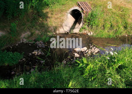 Abwasserkanal, Abflussrohr aus Beton führt Schmutzwasser in einen kleine Bach