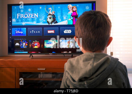 Barcelona, Spain. May 2019: Back view image of cute little boy watching the new Disney plus platform on TV Stock Photo