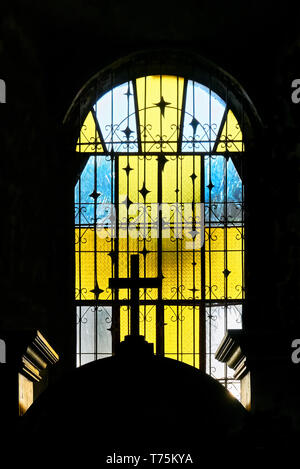 Light shining through a yellow and blue colored stained glass window of St. Catherine of Alexandria church in Leon town, Iloilo Province, Philippines Stock Photo