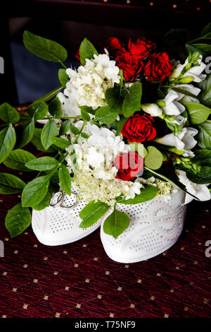 Wedding bouquet next to the bride's shoes and rings Stock Photo