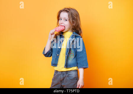 Baby girl kid eating ice cream on yellow background with free text copy space Stock Photo