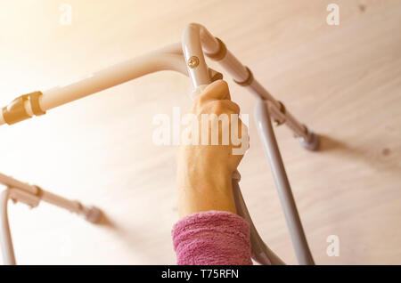 Hands of elderly woman on the handles of a walker. Rehabilitation and healthcare concept. Copy space Stock Photo