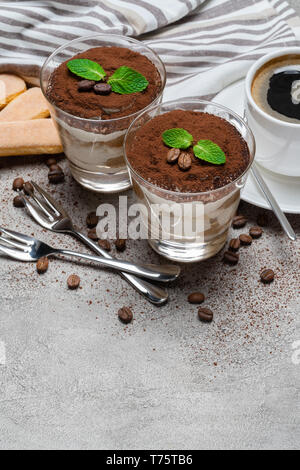 two portions Classic tiramisu dessert in a glass and cup of coffee on concrete background Stock Photo